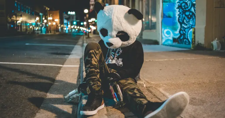 A drunk man sat on the floor with a panda mask on, from the post What are the effects of binge drinking?